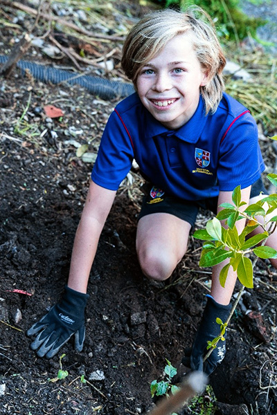 Close up of a maeroa student planting out the gully