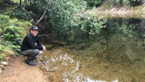 Dave Hamon crouched by a river