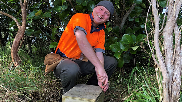 A photo of a man in a high-vis orange shirt holding a pest trap