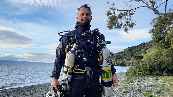 A photo of a man standing with scuba gear on