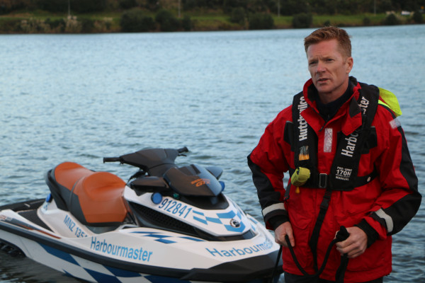 Regional Harbourmaster Chris Bredenbeck wearing a personal flotation device in front of a marked jet ski.